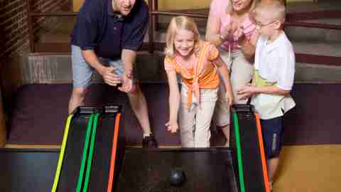 A happy family spending time together and playing games in an arcade, thanks to positive parenting