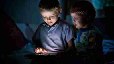 A boy with minecraft addiction plays at night as his brother watches.