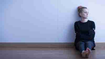 Girl with ADHD and depression sitting on floor by wall