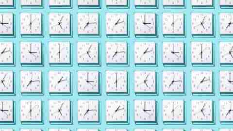 Neatly Arranged White Colored Wall Clocks Displays Different Time on Solid Blue Background.