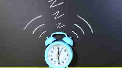 best alarm clock - a blue alarm clock on a bright yellow table