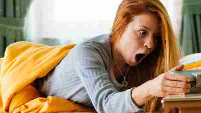 ADHD woman is shocked when she looks at the alarm clock and sees that she overslept