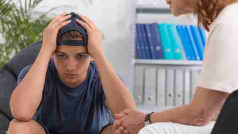 Pissed-off looking teenage boy with oppositional defiant disorder seeing a therapist or counselor