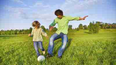 Father and son with ADHD playing soccor outside in field