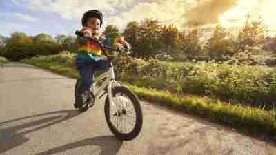Boy with ADHD riding bike on street outside in forested area